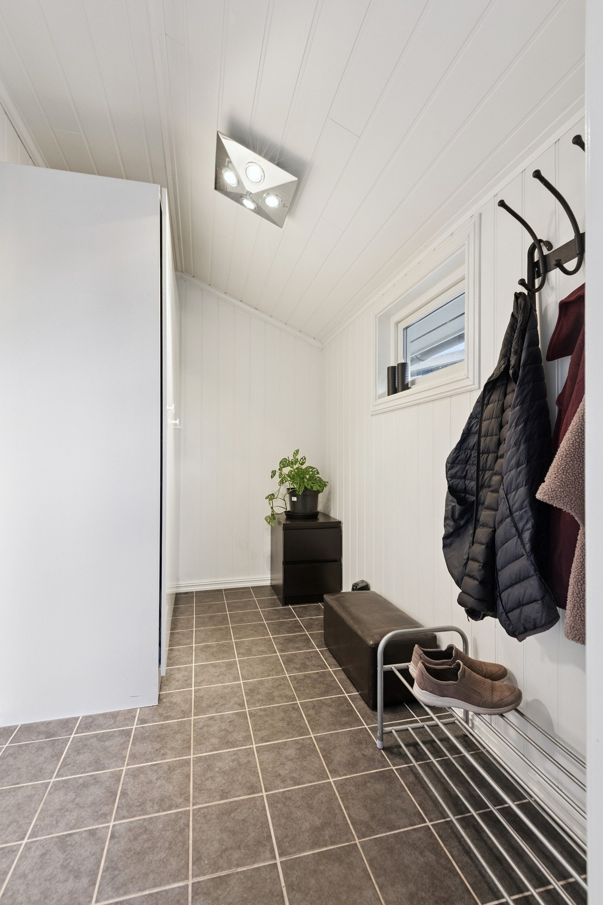 Flislagt gang med plass til å sette sko og henge klær. Galleribilde