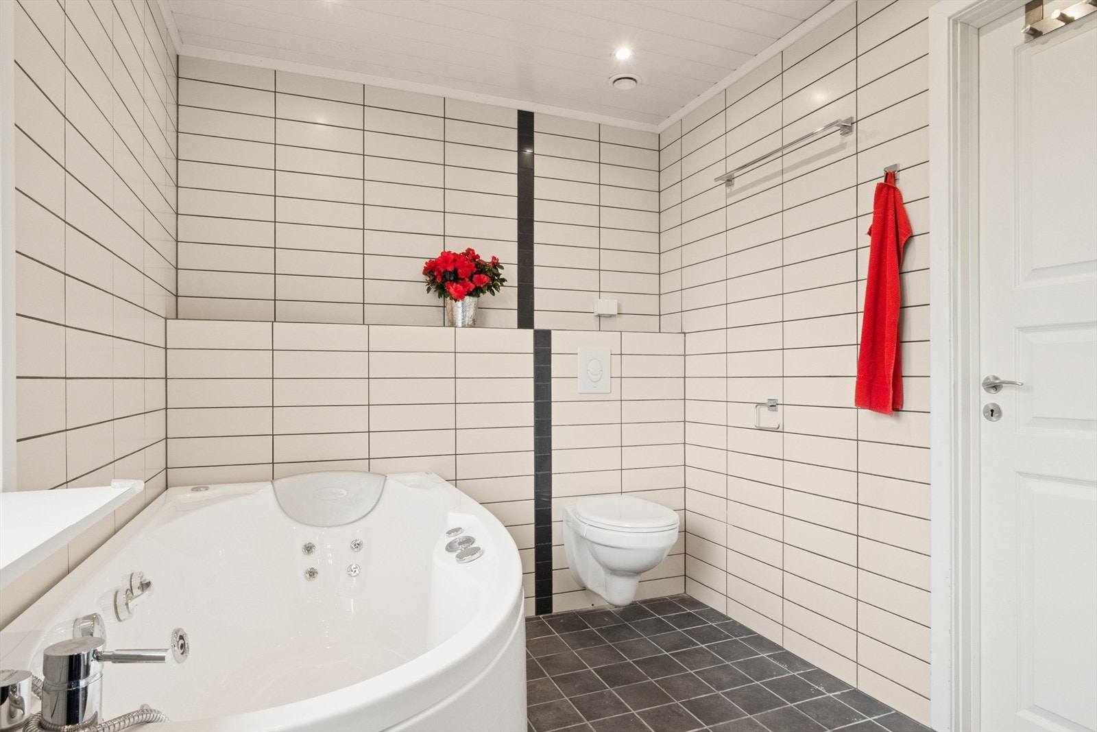 Badet er innredet med heldekkende servant med underskap, veggmontert toalett, dusjhjørne med herdet glassdør og boblebadekar. Galleribilde