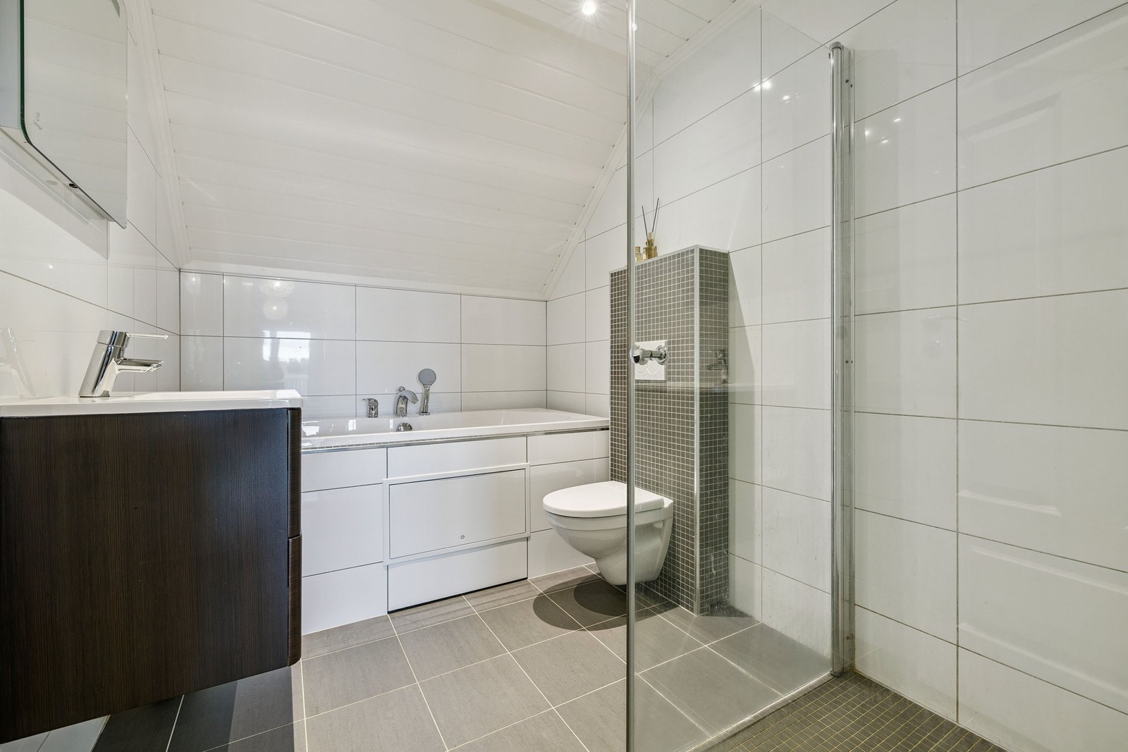 Badet i 2 etg er innredet med innbygget badekar, servantskap med dempere på skuffene, speil, dusjhjørne med glassdører og vegghengt wc med innebygget sisterne. Galleribilde