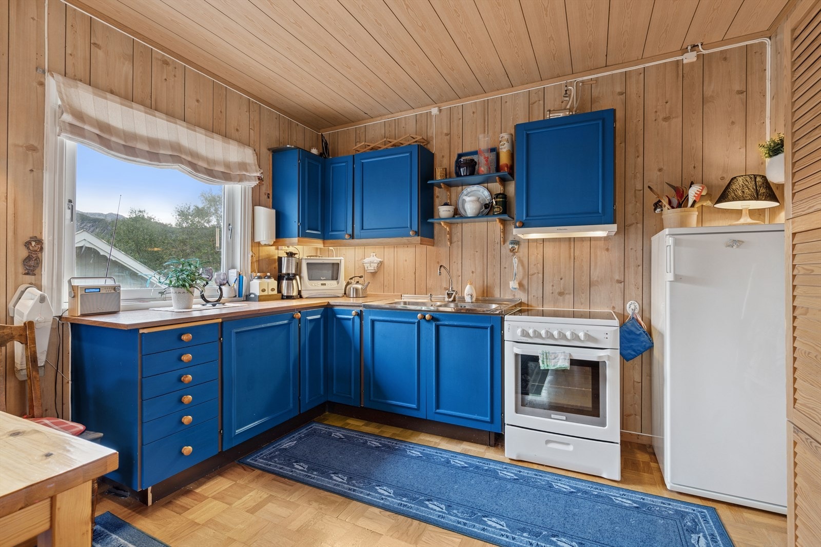 Kjøkkenet har innredning med malte profilerte fronter og laminat benkeplate med nedfelt vask. Det er påvist slitasje på kjøkkenet. Kjøkkenet har mekanisk avtrekk fra kjøkkenventilator. Det er frittstående kjøleskap og komfyr. Galleribilde