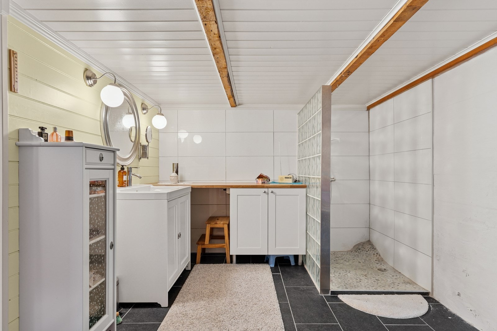 Fliser på gulv med varmekabler, betongvegger og fliser på vegger. Rommet er utstyrt med innredning med nedfelt servant. Det er sprekker og løse fliser på vegger, samt bom i gulvfliser. Galleribilde