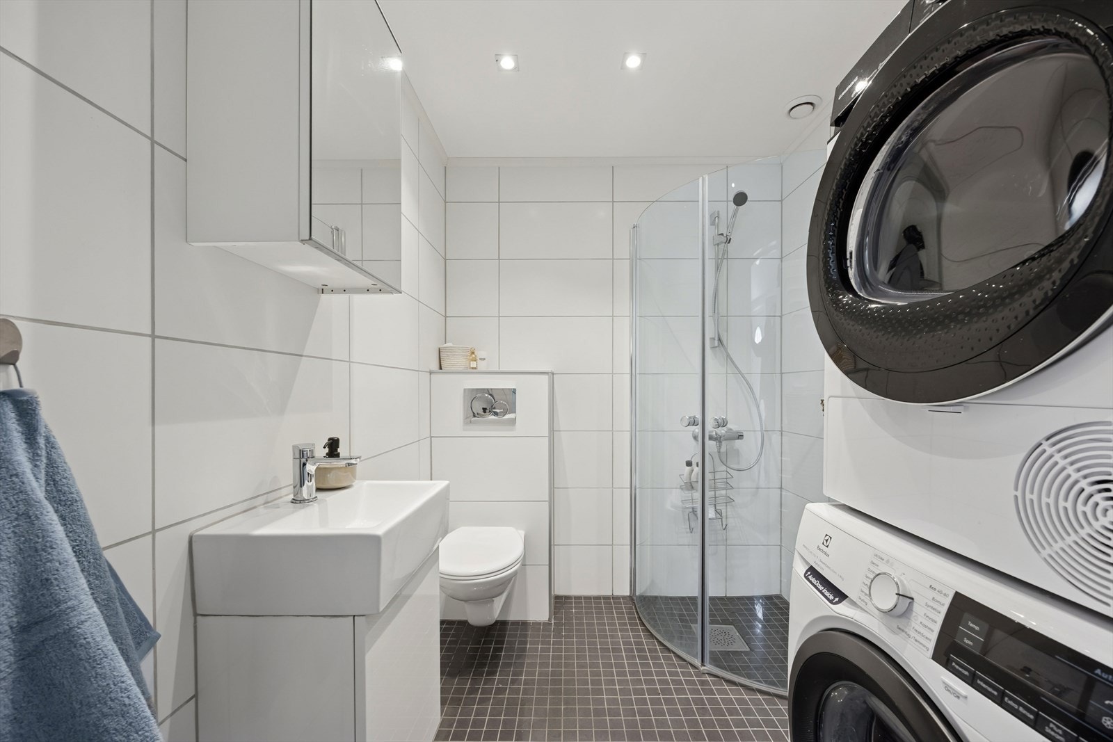 Badet i 1. etasje er pent innredet med flislagte overflater, vegghengt toalett, dusjhjørne og servant med underskap. Galleribilde