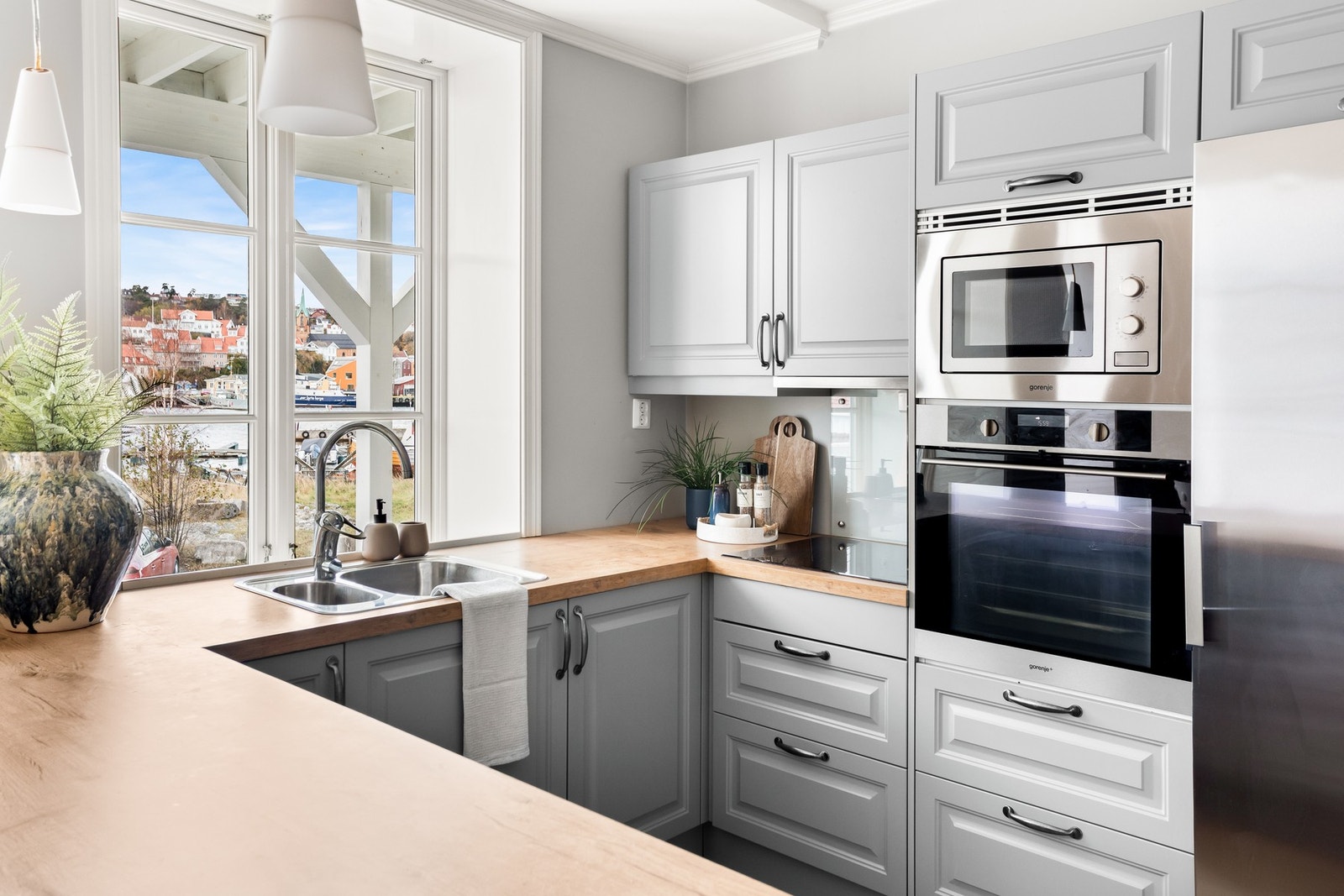 Benkeplaten har integrert vask og induksjonstopp, og alle hvitevarer er integrert for et rent og helhetlig uttrykk. Galleribilde