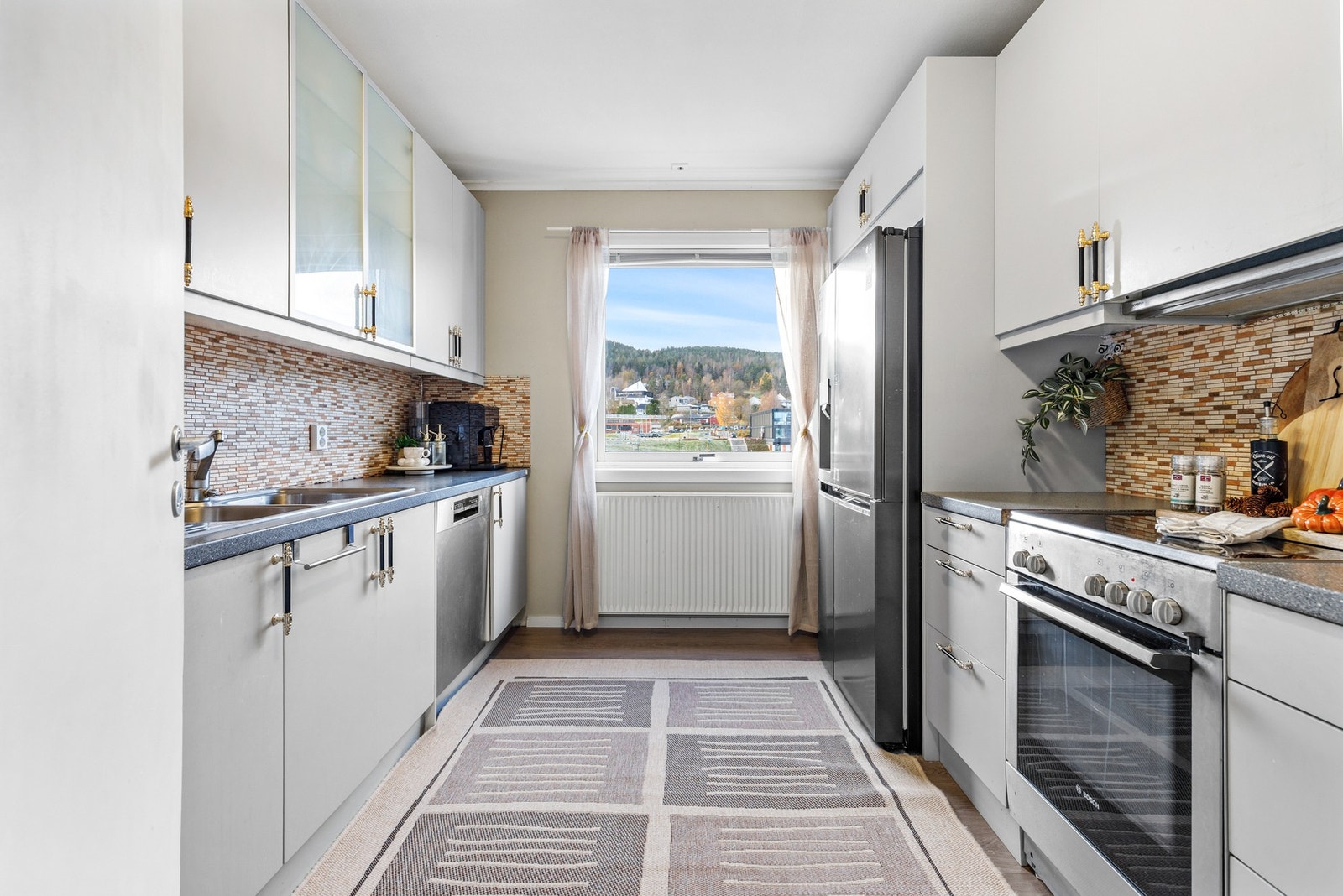 Kjøkkeninnredning med med slette fronter og benkeplate i laminat og nedfelt stålvask med ettgreps blandebatteri Galleribilde