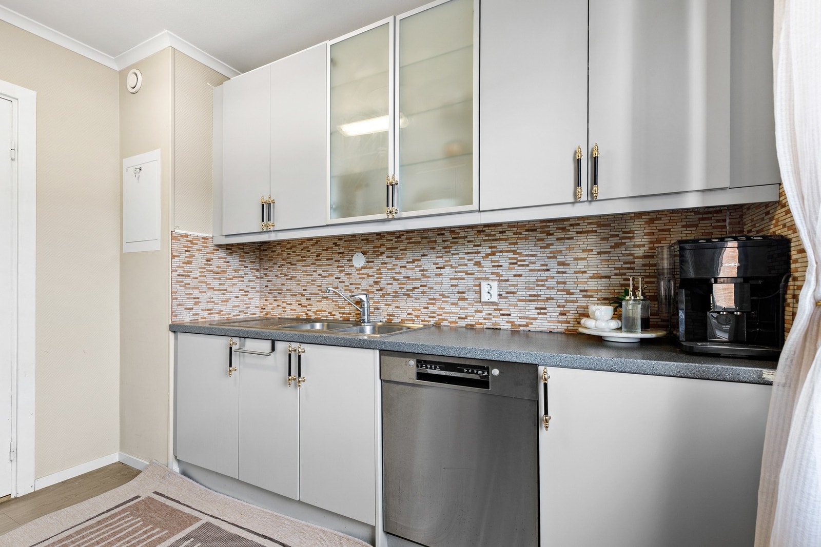 Innredningen er utstyrt med hvitevarer som kjøl-/fryseskap, oppvaskmaskin, mikrobølgeovn og komfyr Galleribilde