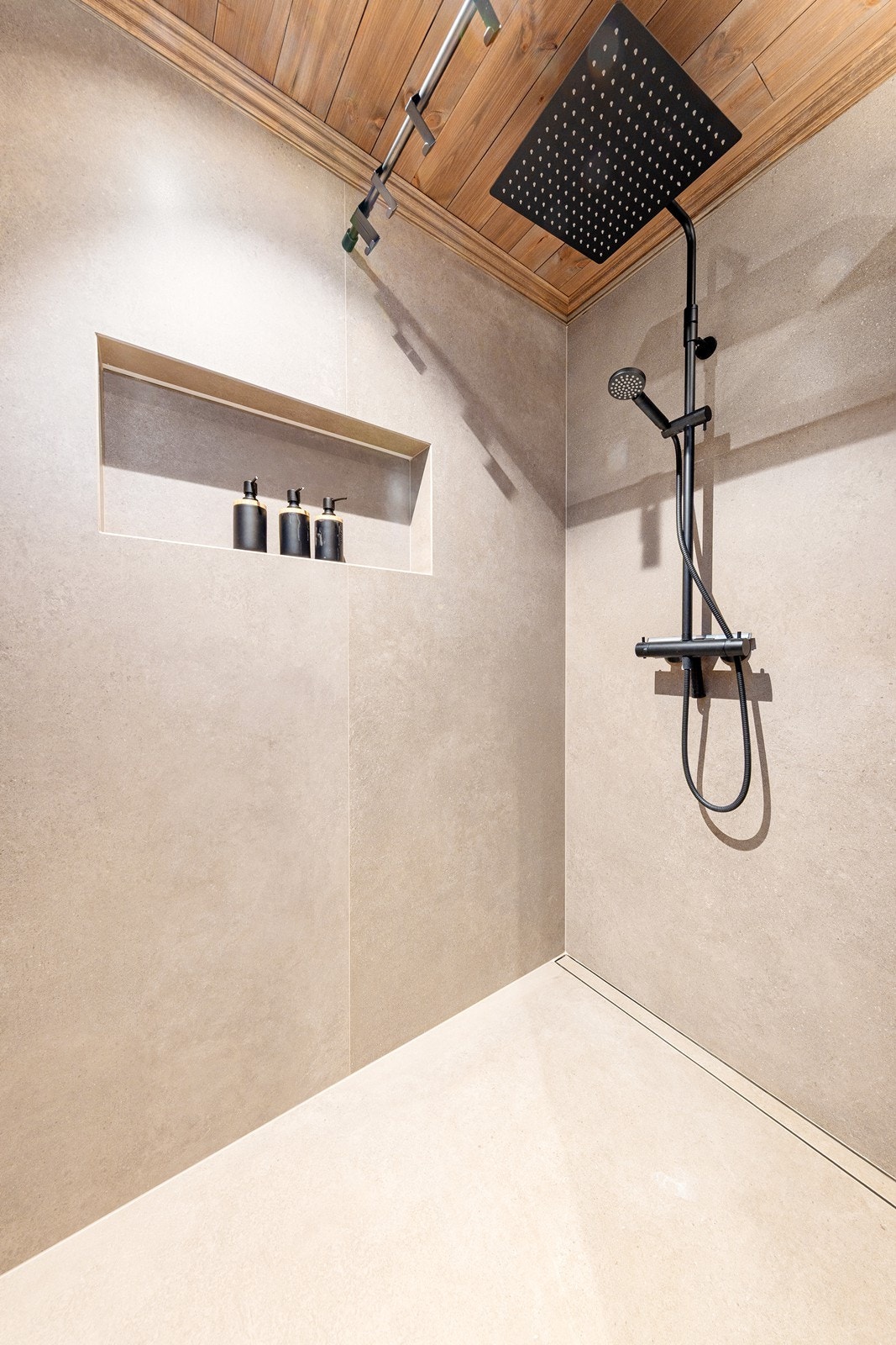 I dusjen er det en praktisk nisje for oppbevaring av såpe og tilbehør. Badet har moderne uttrykk med svarte detaljer. Galleribilde