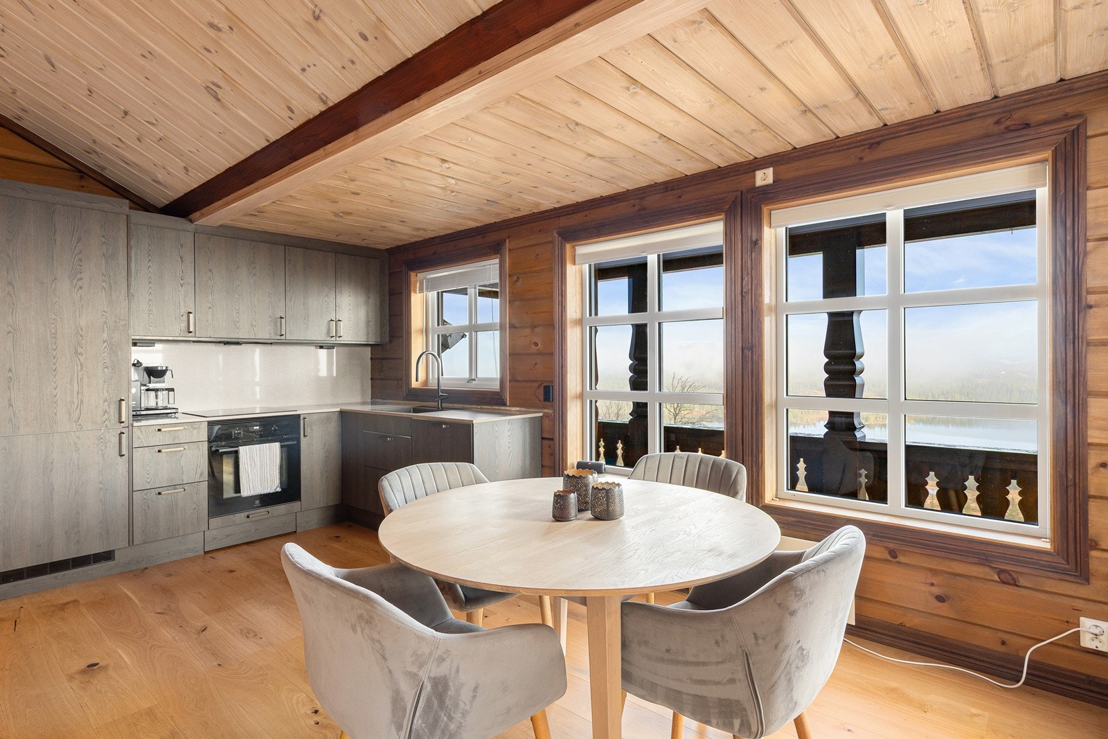 Pent moderne kjøkken med mørke slette fronter og benkeplate av stein. Kjøkkenet er utstyrt med innfelte hvitevarer som oppvaskmaskin, kjøl/fryseskap, platetopp og stekeovn. Galleribilde