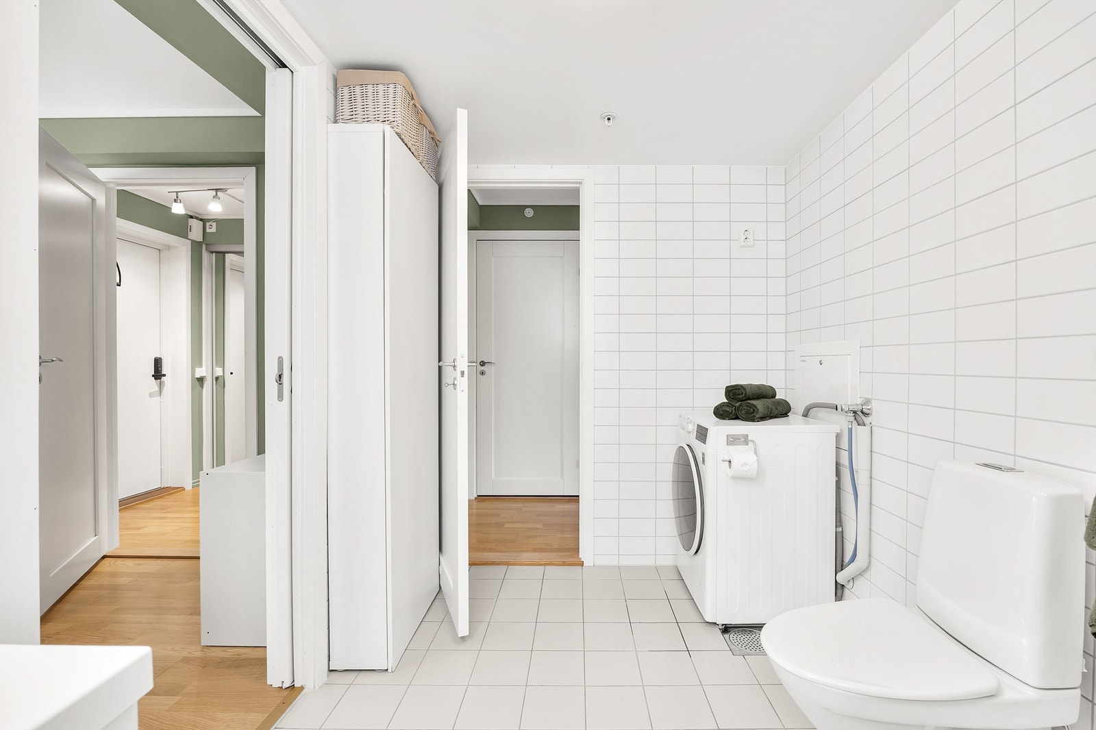 Lys bad med flislagt gulv og vegger med varme i gulv. Det er lagt opp til bruk av vaskemaskin på badet. Galleribilde