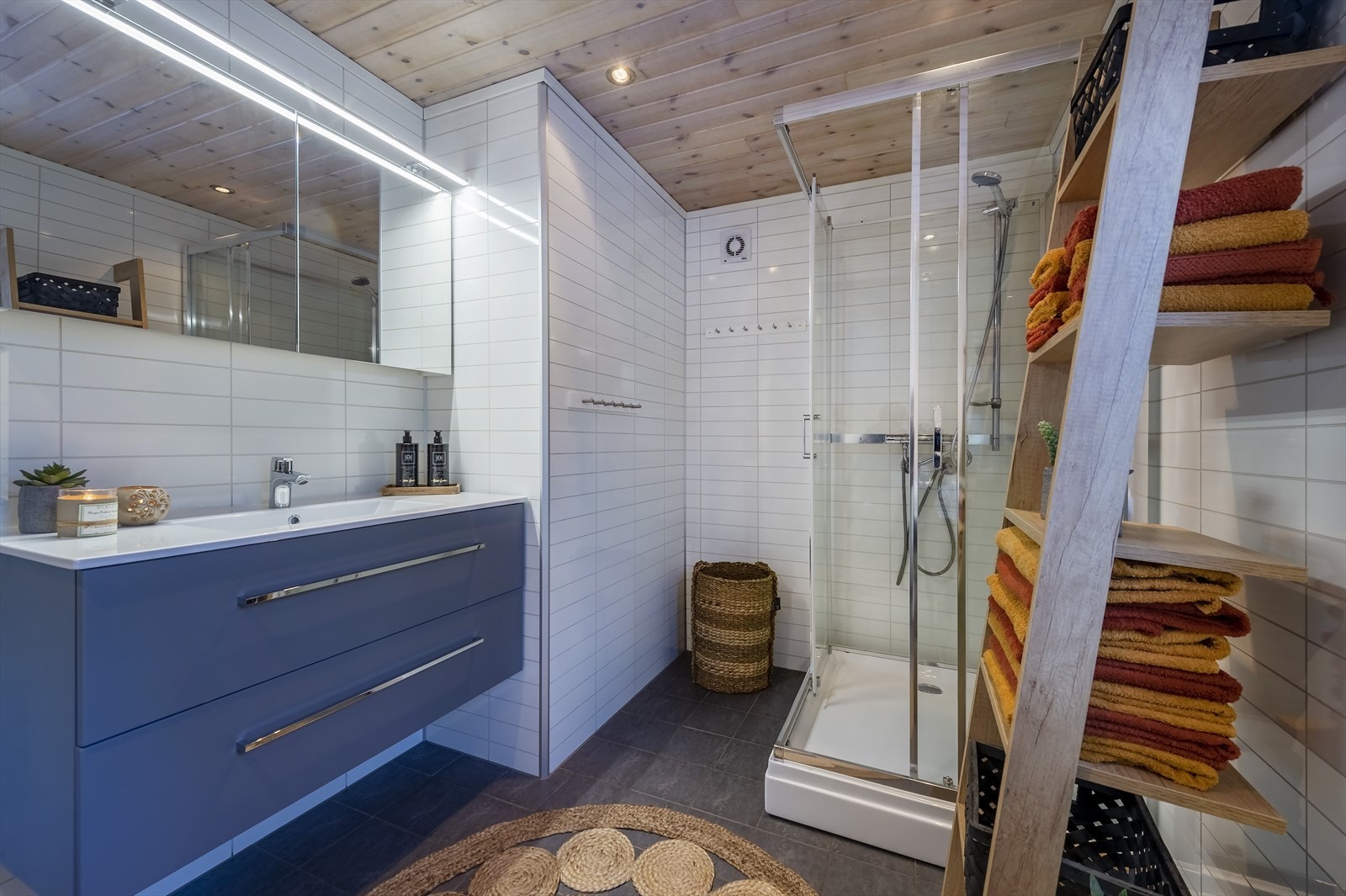 Badet er innredet med nedfelt servant, veggmontert toalett, dusjkabinett og opplegg for vaskemaskin. Galleribilde