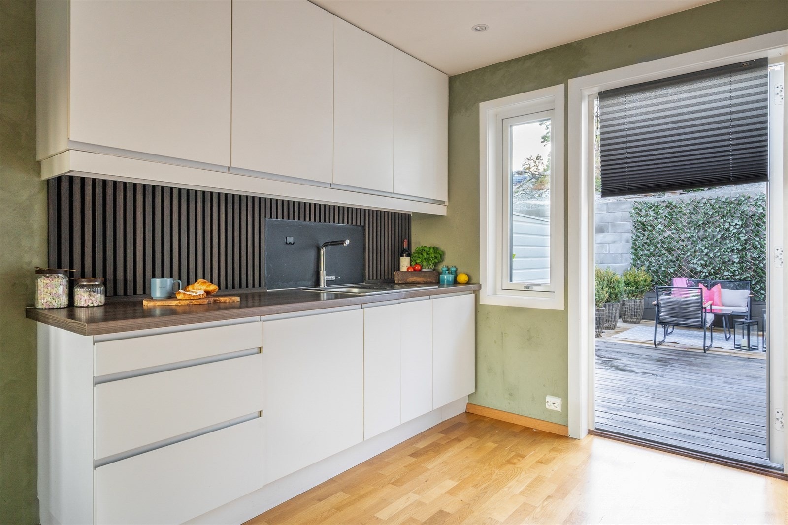 Kjøkkenet har innredning med glatte fronter. Benkeplaten er av laminat og det er spiler mellom over- og underskap. Det følger med kjøl/fryseskap, oppvaskmaskin, platetopp, stekeovn og komfyrvakt. Galleribilde