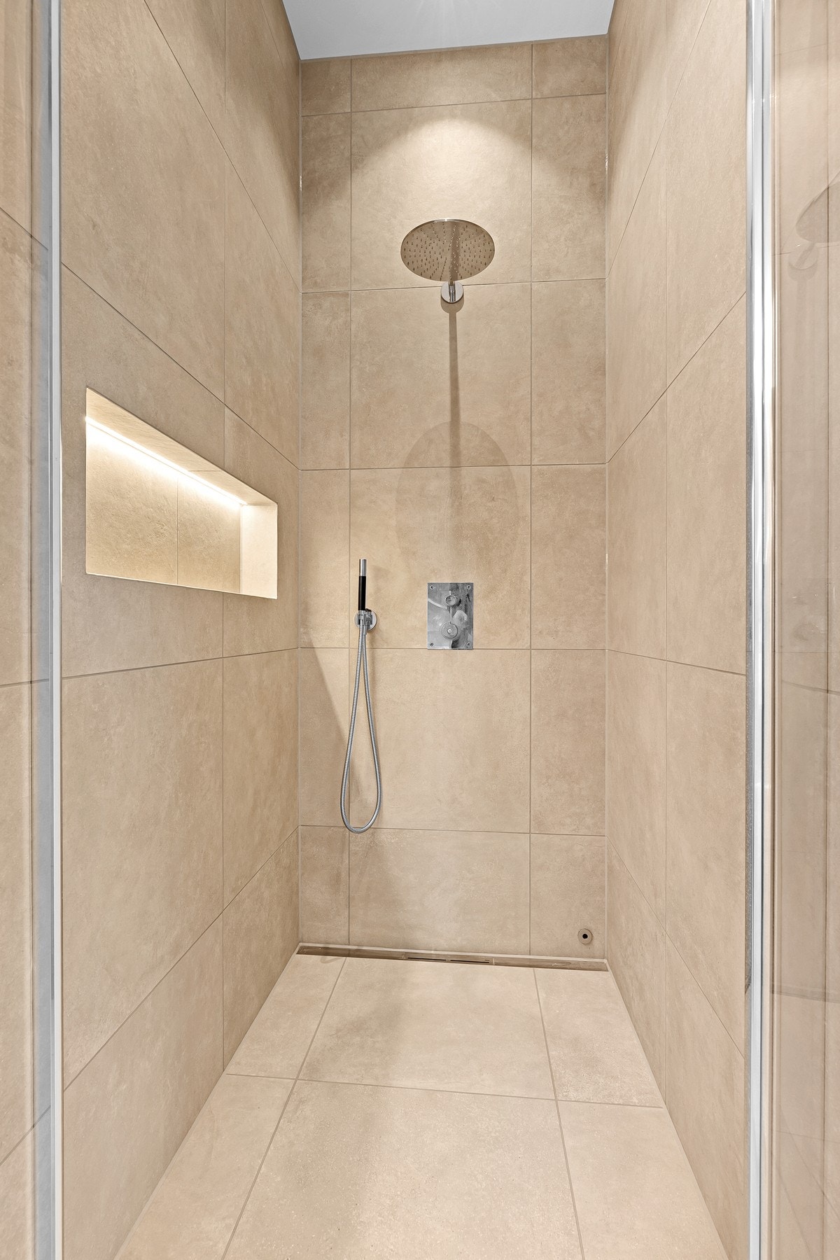 Badet er innredet med vegghengt toalett, servant med innredning, badekar og dusjnisje. Galleribilde