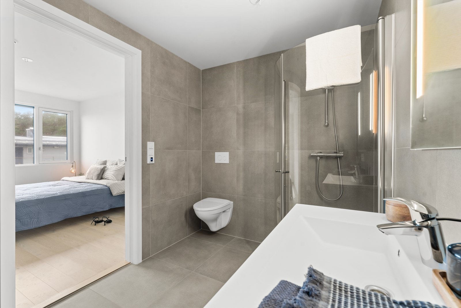 Pent, flislagt gulv og vegger. Vegghengt klosett, servant og dusjhjørne. Galleribilde