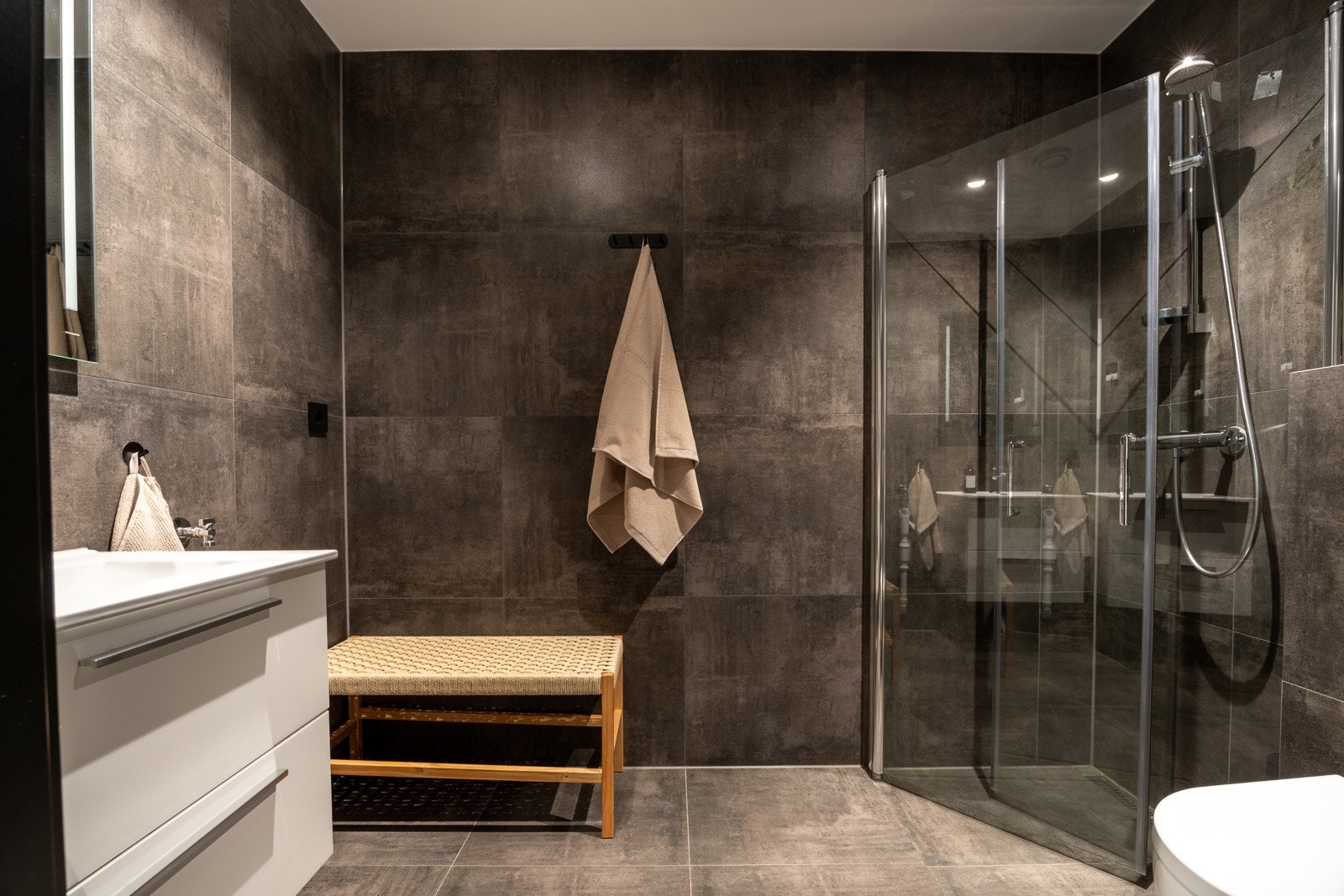 Et flott bad med store gulv- og veggfliser (60 x 60 cm fliser). Vannbåren gulvvarme som varmekilde og belysningen består av dimbare LED-spotter og lys integrert i speil.