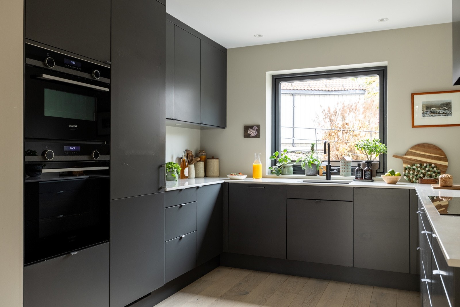 Et stort moderne kjøkken med innredning fra Sigdal med slette fronter og benkeplate i kompositt. Stort vindu mot nord/inngangspartiet.