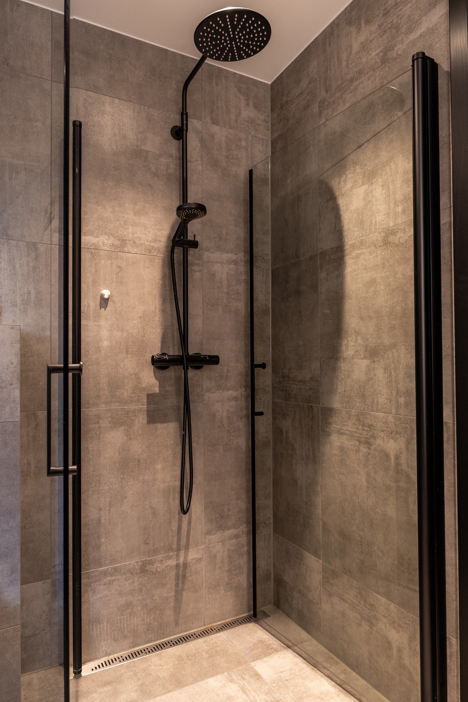 Familiebadet har dusjhjørne med innfellbare dusjdører. Dusjen er utstyrt med regnfallsdusj og håndholdt dusjspyler.