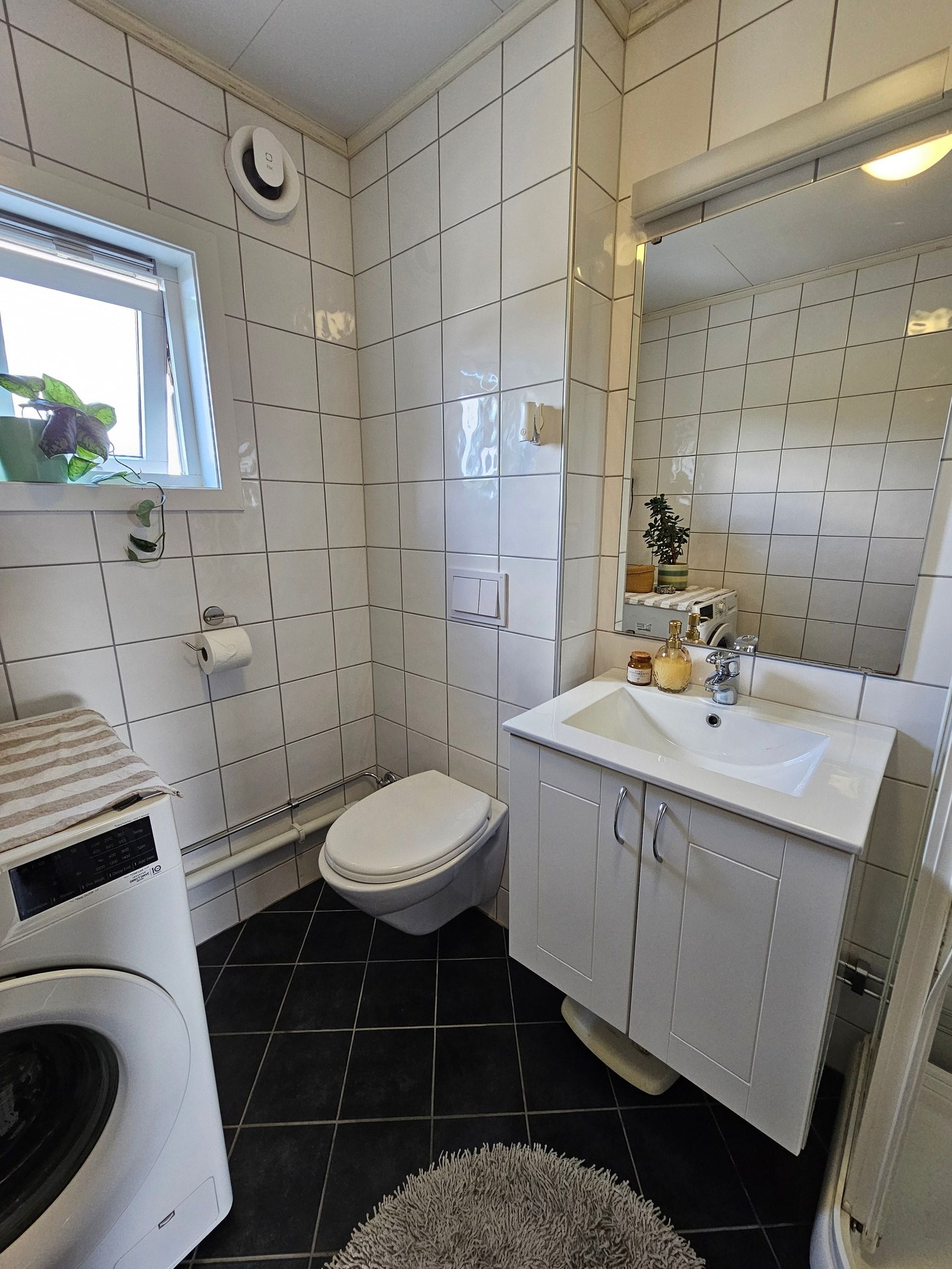 Praktiske hvite fliser på veggene, lette å holde rene og det er enkelt å style badet til den stemningen man ønsker selv. Galleribilde