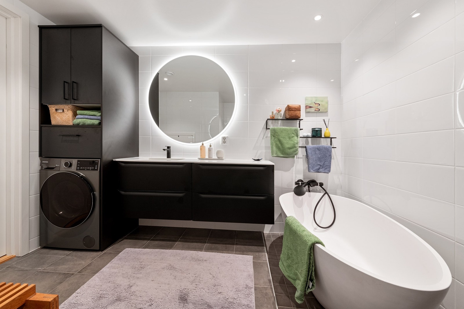 Baderomsinnredning fra Linnbad med Corian benkeplate. Rundt speil med lys fra Vikingbad. Opplegg for vaskamskin Galleribilde