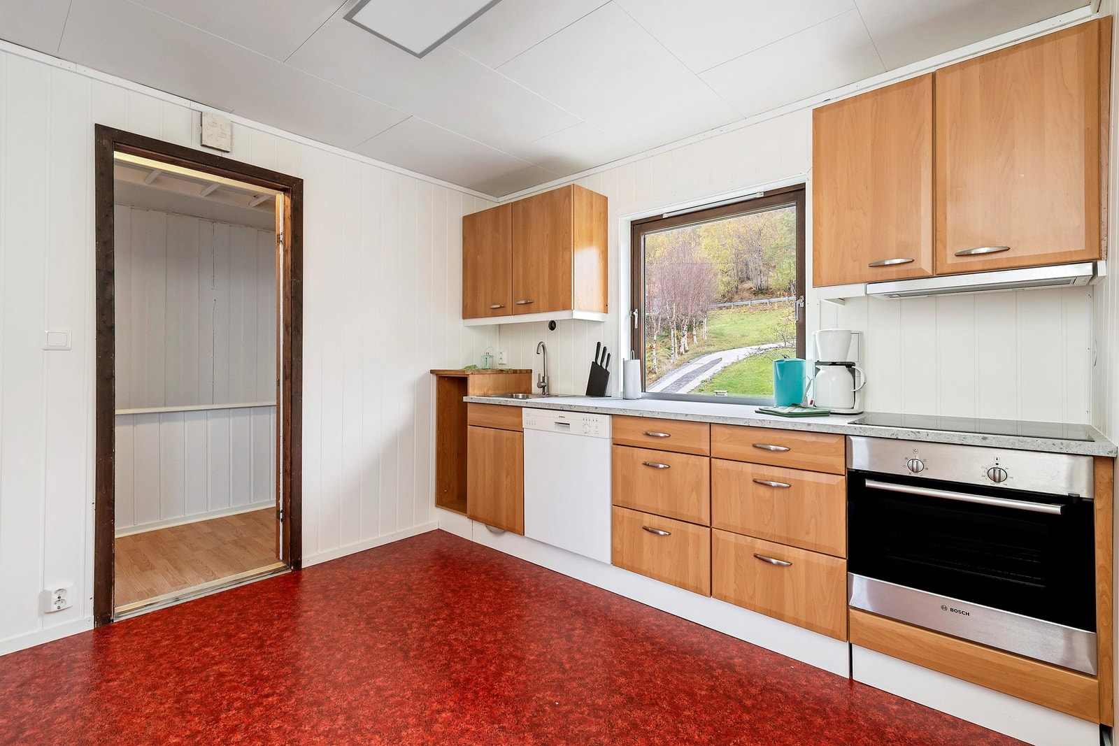 Boligens andre kjøkken. Innredningen består av skap med glatte fronter og benkeplate i laminat. Det er integrerte hvitevarer som stekeovn, platetopp, oppvaskmaskin og et frittstående kjøleskap. Galleribilde