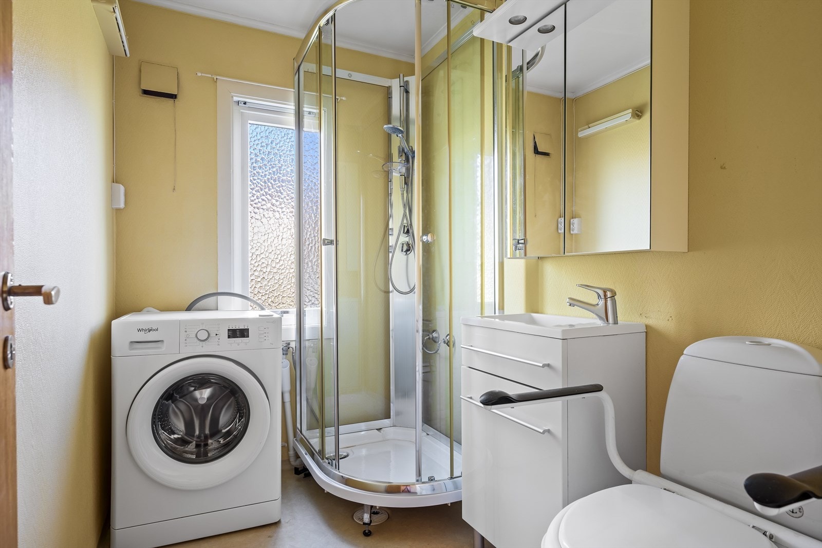 Badet er innredet med dusjkabinett, servant med underskap, wc og opplegg for vaskemaskin. Galleribilde