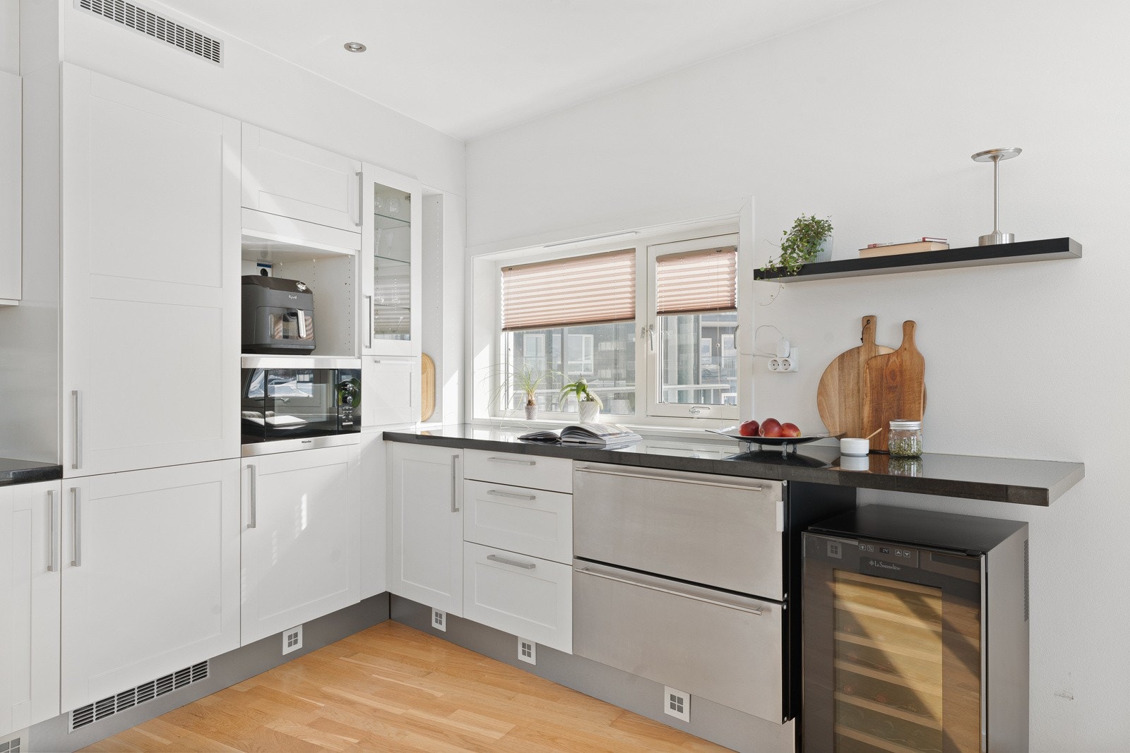 Kjøkkenet fremstår som tidløst og moderne med integrerte hvitevarer som inkluderer stekeovn med koketopp, oppvaskmaskin, vinkjøler, kjøleskap med fryser og innebygd ismaskin. Galleribilde