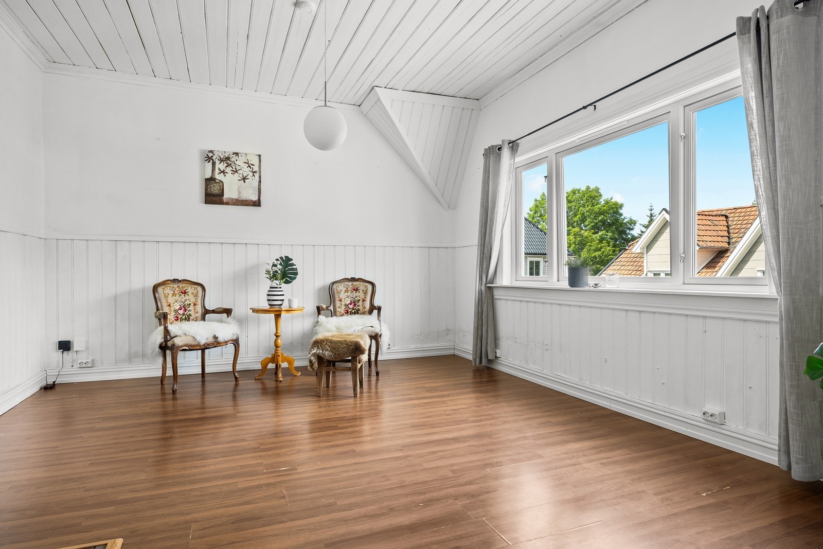 Den doble stuen har store vindusflater og lyse veggflater med brystningspanel. Galleribilde