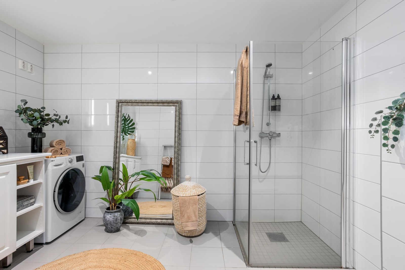 Romslig baderom med gulvfliser med varme under samt veggfliser og utstrakt bruk av downlights. Galleribilde