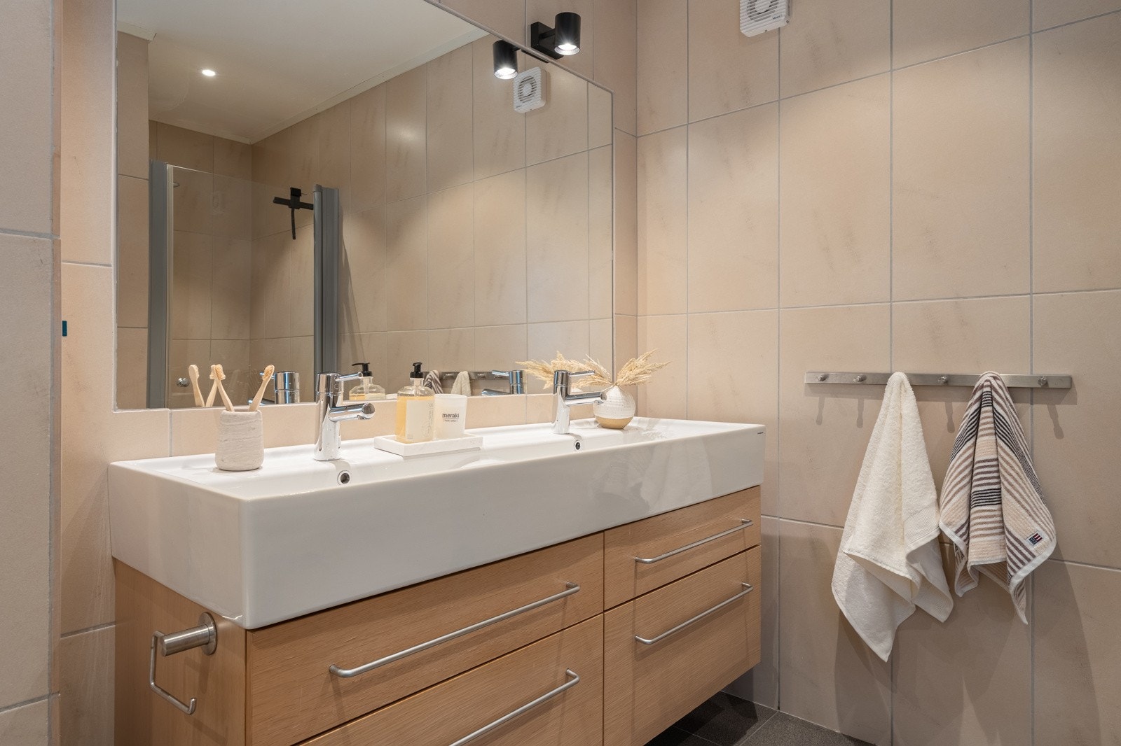 Baderomsinnredning med dobbel servant og speil med belysning.