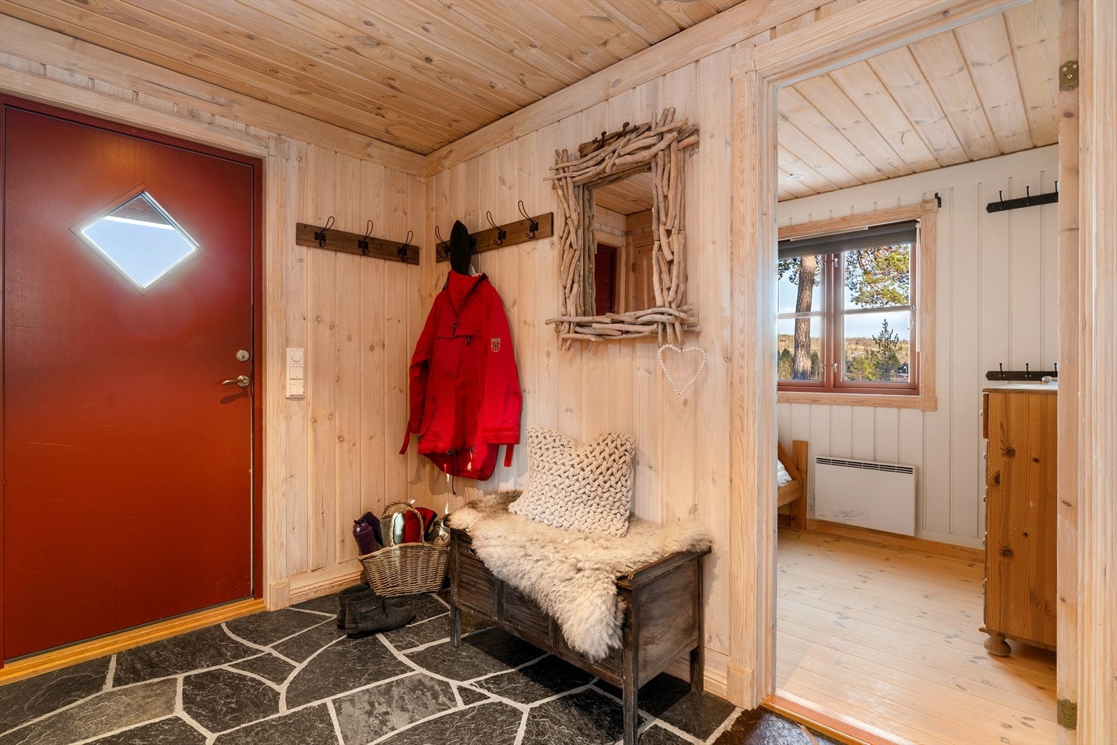 Velkommen inn! Man ankommer hytta via et takoverbygget inngangsparti og inn til en romslig entré med fliser på gulv. Galleribilde