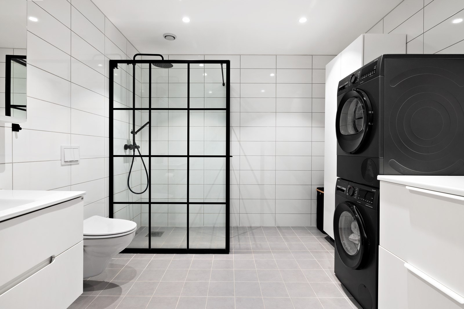 Badet er utstyrt med dusjhjørne, servant med underskap, speil med belysning, vegghengt toalett og opplegg for vaskemaskin og tørketrommel. Galleribilde