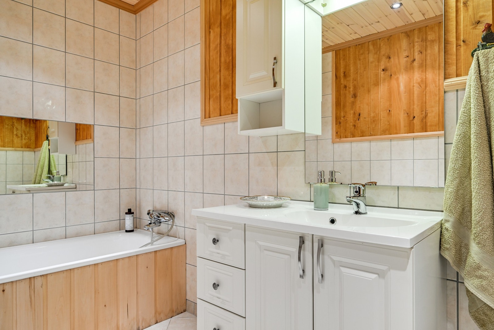 Det er flis på gulv og vegger, samt delvis kledd i bjerkepanel. Badet har en solid innredning i hvitt, og taket er av panel med spottbelysning. Galleribilde