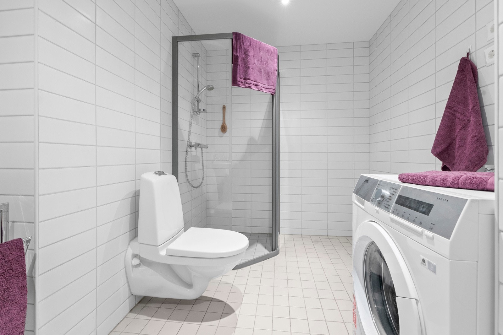 Videre har rommet opplegg for vaskemaskin, veggmontert toalett og dushjørne med herdet glass Galleribilde