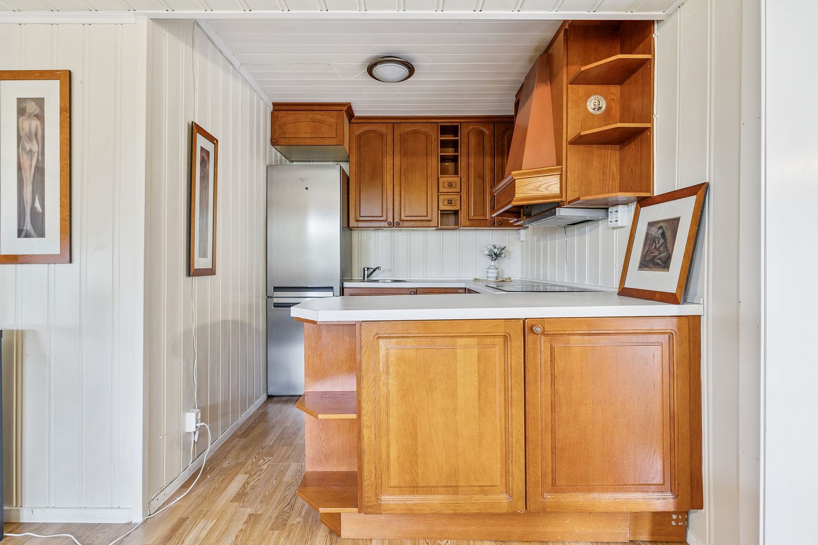 Kjøkkenet er innredet med kjøleskap, platetopp og stekeovn Galleribilde