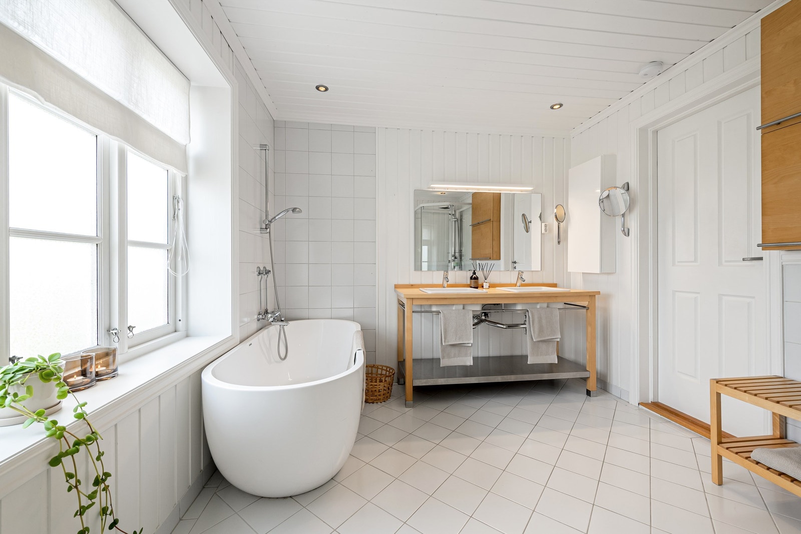 Bad i 2. etsje fra 2011. Badet er utstyrt med vegghengt wc, frittstående badekar med vegghengt armatur og dusjkabinett. Baderomsinnredning med to servanter nedsenket i steinplate. Speil og lite veggmontert skap over servanter. Galleribilde