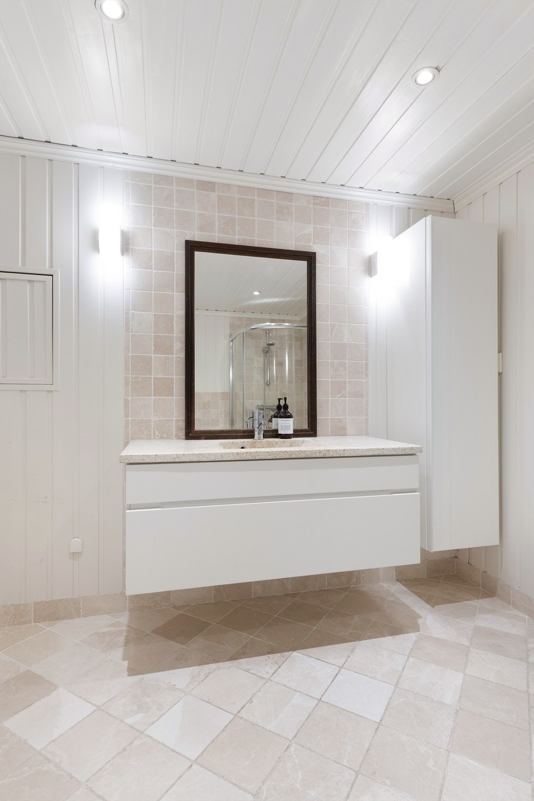 Hvit baderomsinnredning med ovenpåliggende servant med ett-greps armatur. Galleribilde