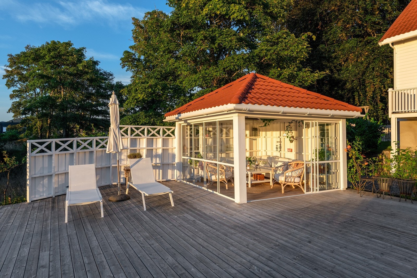 Hagestue med glassvegger og stor terrasseplatting i hagen Galleribilde