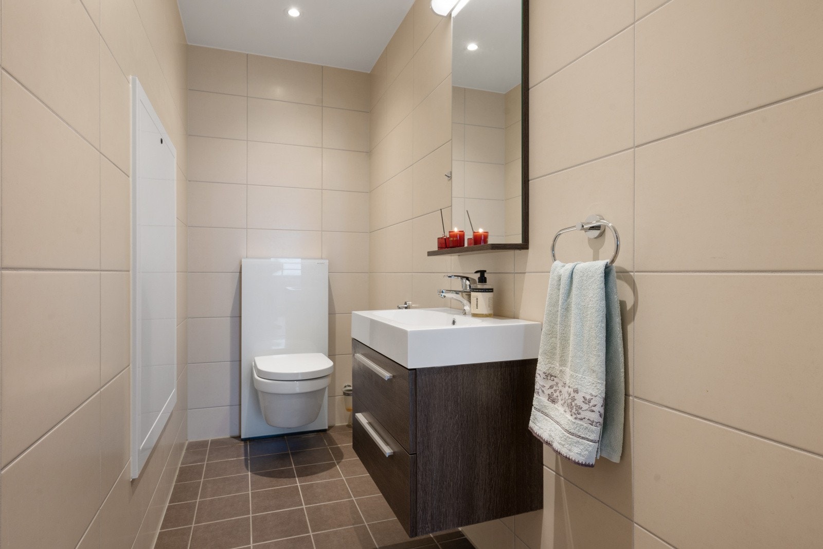 Toalettrommet har fliser på gulv, malte flater på vegg og plater i tak. Rommet er utstyrt med vegghengt wc og solid baderomsinnredning med servant med skuffer og ett-greps blandebatteri. Galleribilde