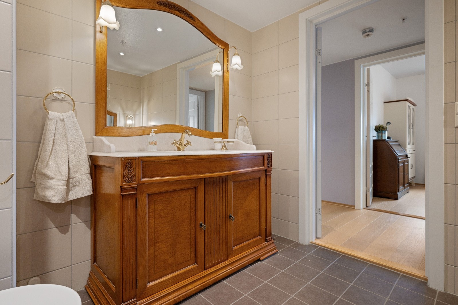 Solid baderomsinnredning i gammel stil. Speil med lampetter og marmor servantplate. Galleribilde