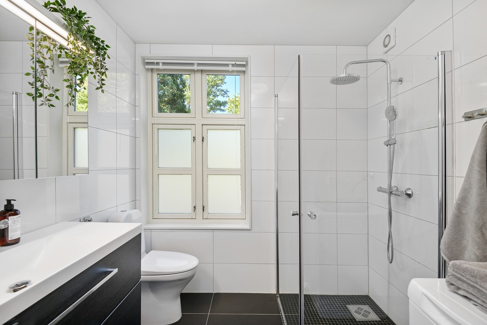 Baderomsinnredningen, speilskap, toalett, dusjhjørne og opplegg for vaskemaskin. Galleribilde