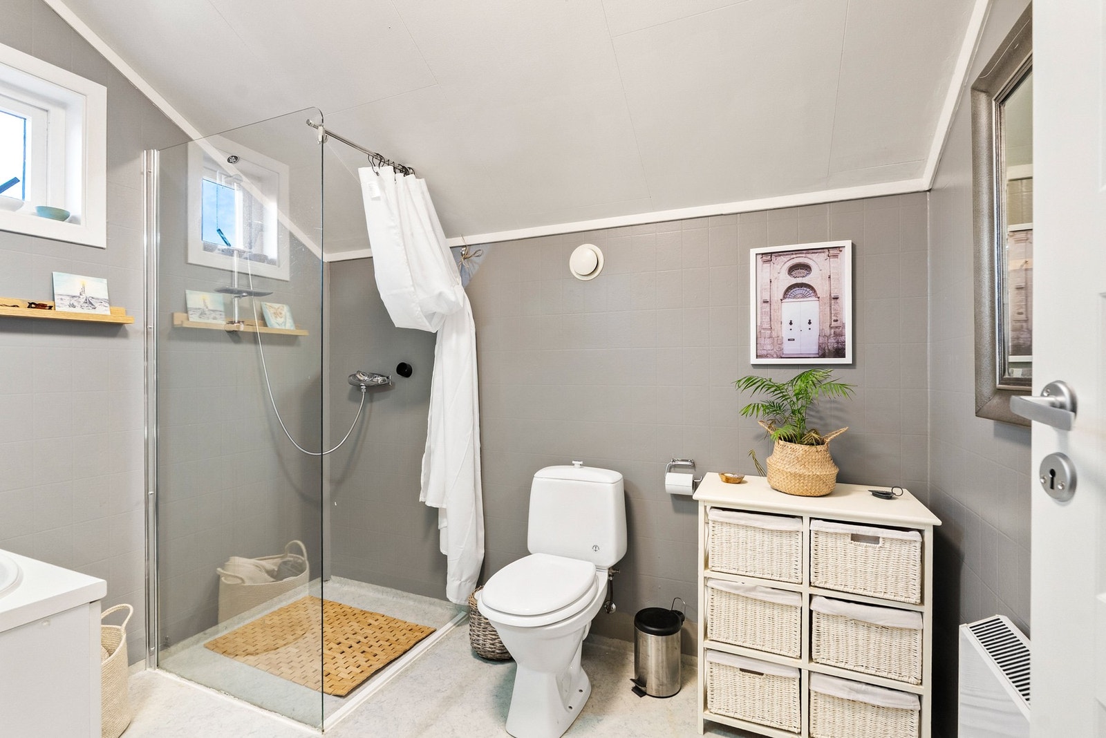 Badet i loftsetasjen med toalett og dusjhjørne med glassvegger. Galleribilde