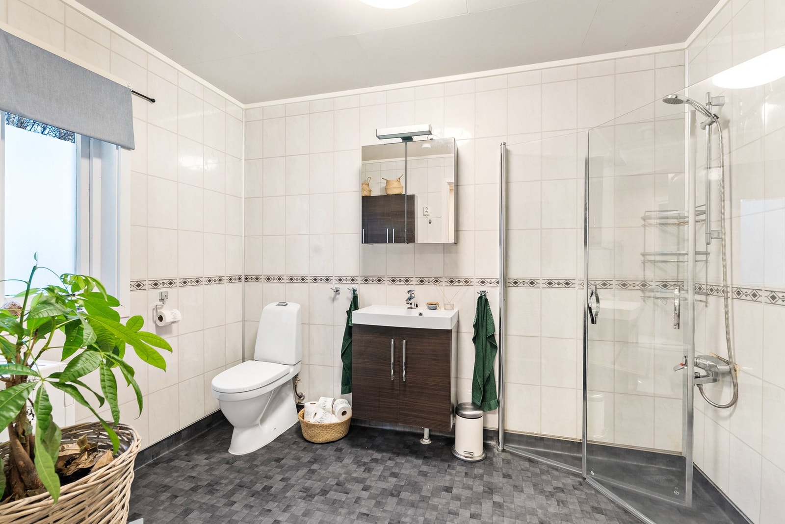 Badet i 1. etasje har innredning med speilskap og servant, toalett og dusjvegger/hjørne. Galleribilde