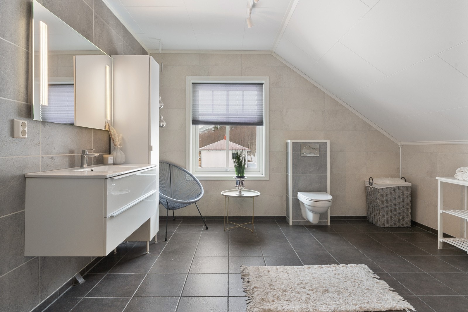 Flislagt bad med lys baderomsinnredning som sikrer godt med oppbevaringsplass.