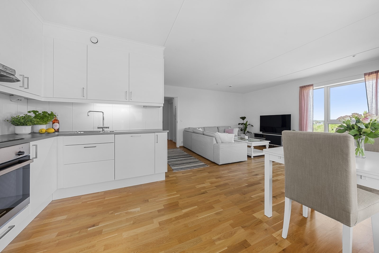 Lyst og pent kjøkken med integrete hvitevarer i åpen løsning med stuen Galleribilde