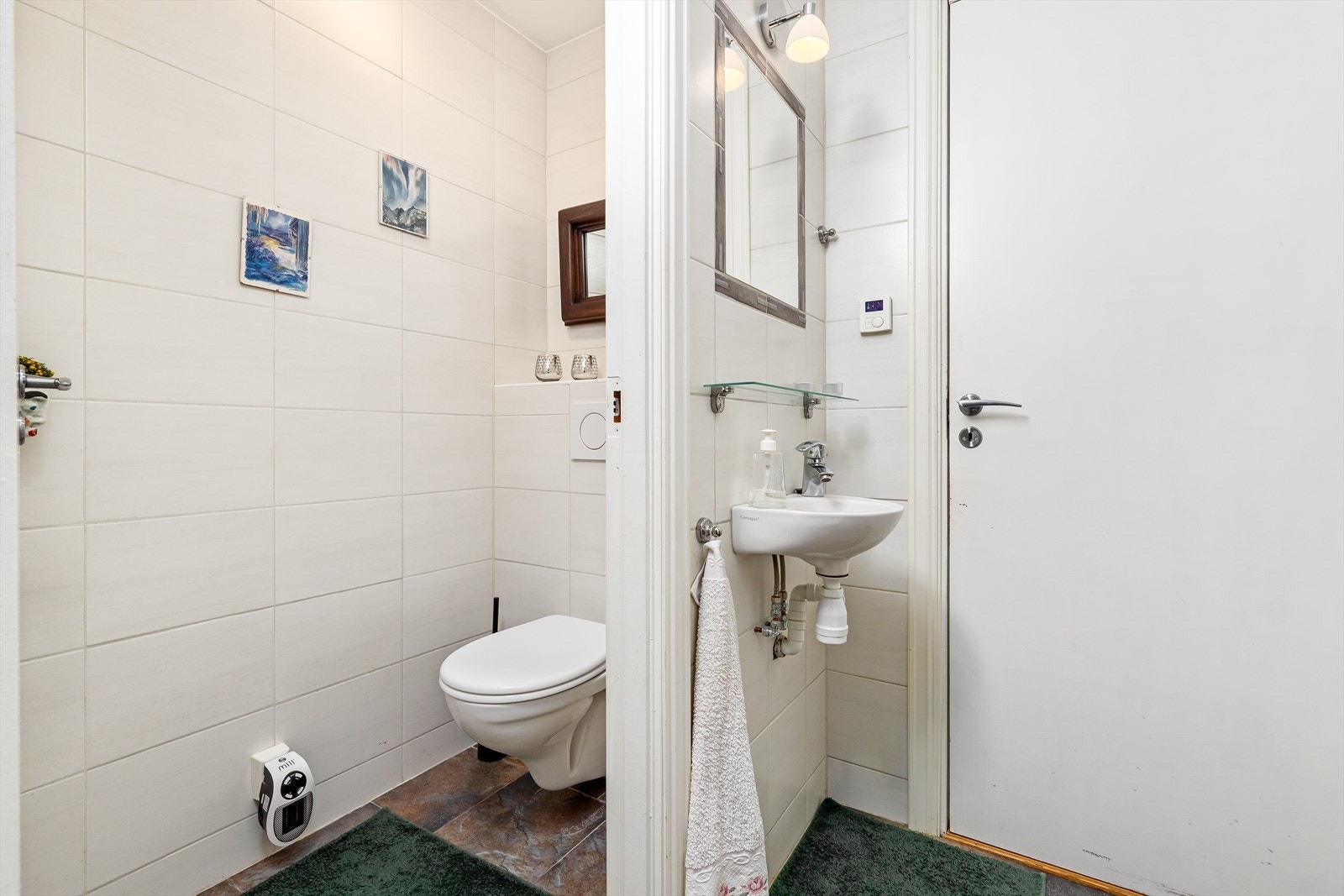 WC-rom med vegghengt toalett og enkel servant på vegg. Galleribilde