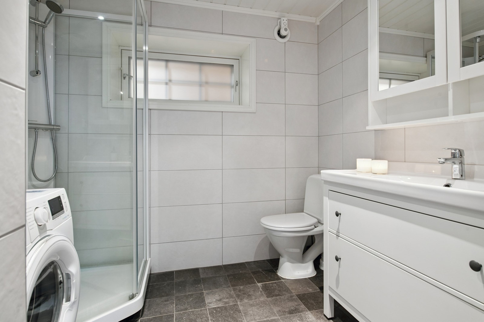 Badet i sokkelen er flislagt og har dusjhjørne og opplegg for vaskemaskin. Galleribilde