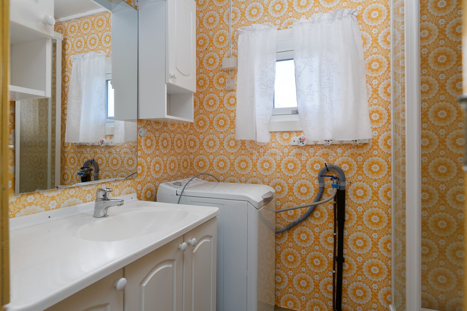 Bad/vaskerom fra 1987 med servant på innredning, dusjkabinett, toalett og opplegg for vaskemaskin. Galleribilde