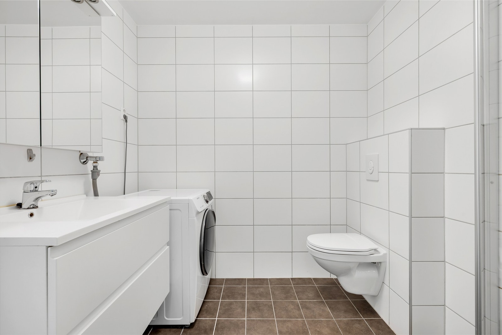 Badet i 1. etasje er et lyst og moderne bad med vegghengt WC, baderomsinnredning og opplegg for vaskemaskin. Galleribilde