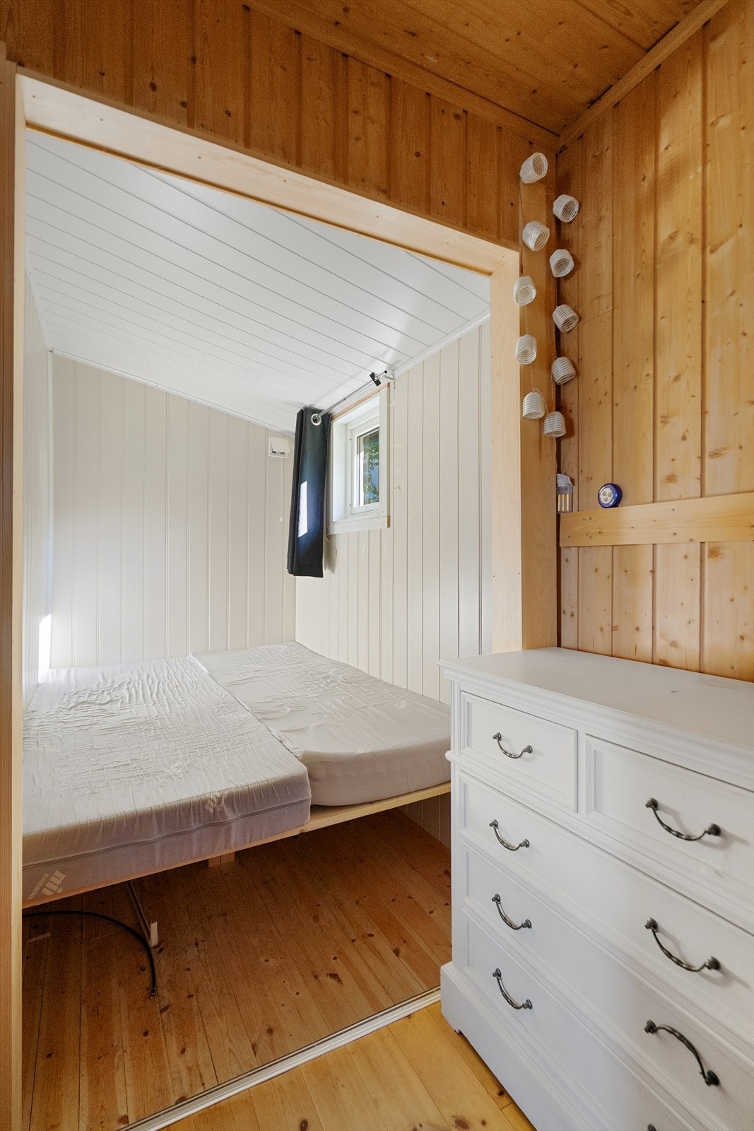 Hyggelig soverom med panel vegger og vindu som gir naturlig lys Galleribilde