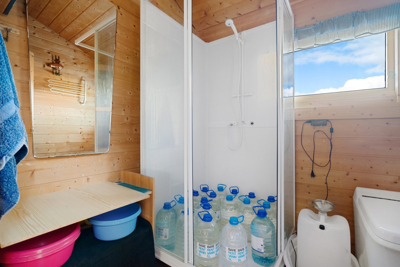 Bad med dusjkabinett og toalett. Panelet på veggene gir en varm og koselig hyttefølelsn Galleribilde