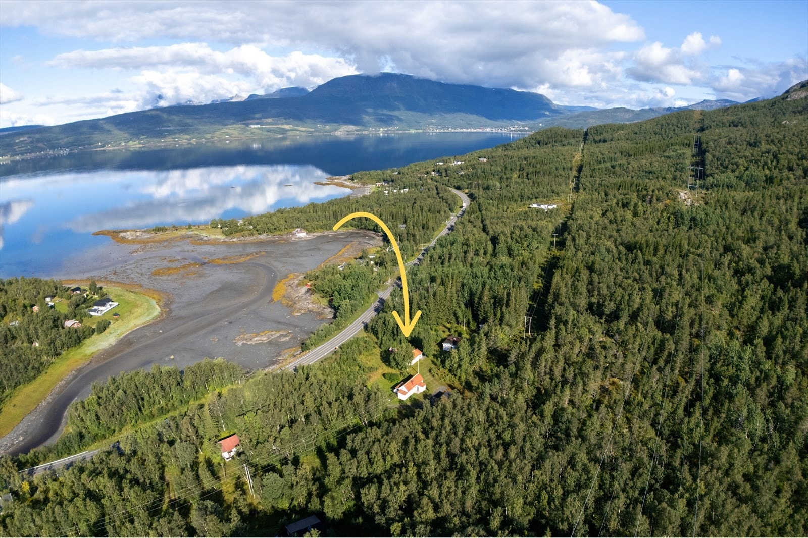 Oversiktsbilde som viser hyttas flotte beliggenhet med nærhet til sjøen og omgitt av vakker natur Galleribilde
