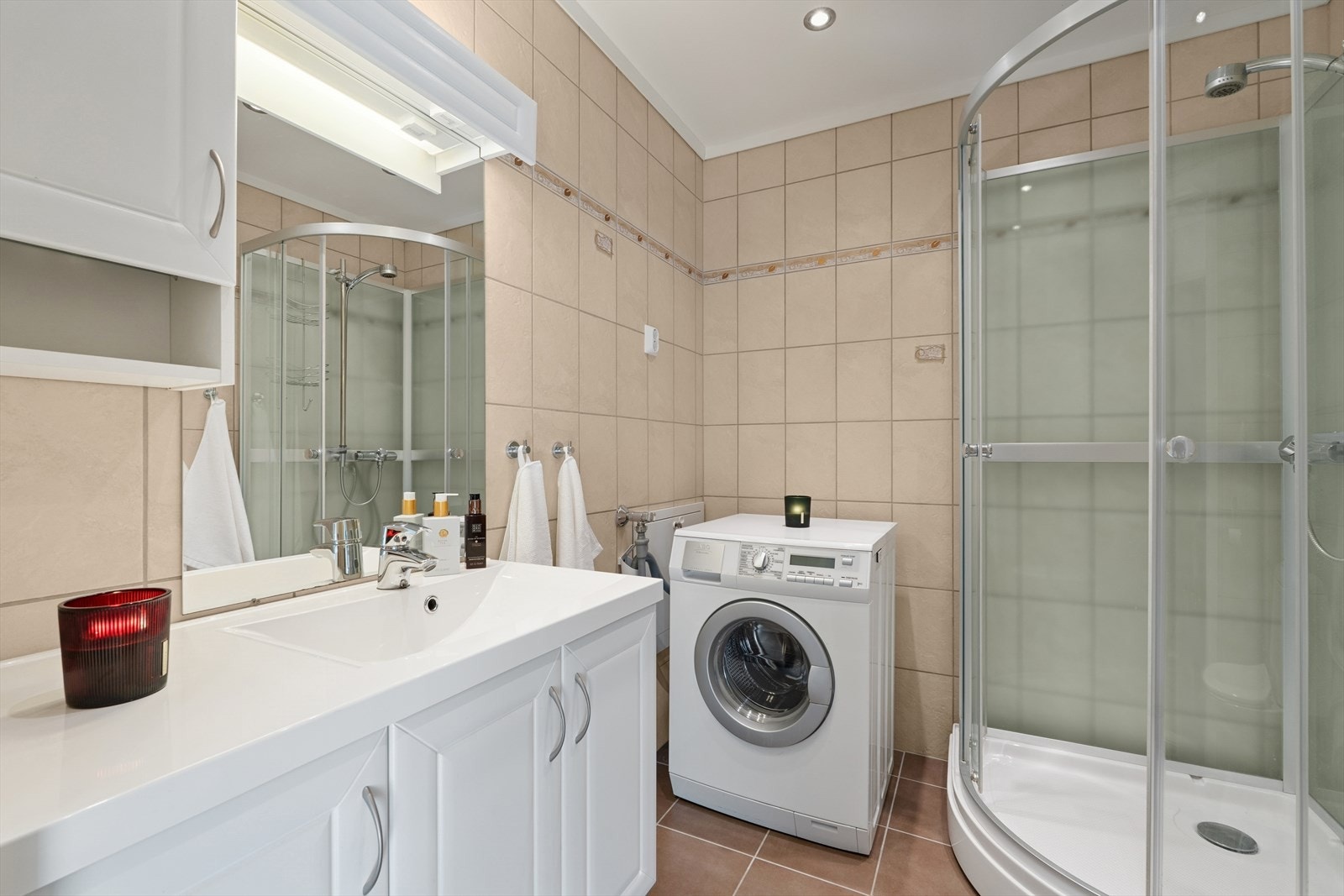 Baderom med fliser og varmekabler. Her er det opplegg for vaskemaskin. Galleribilde